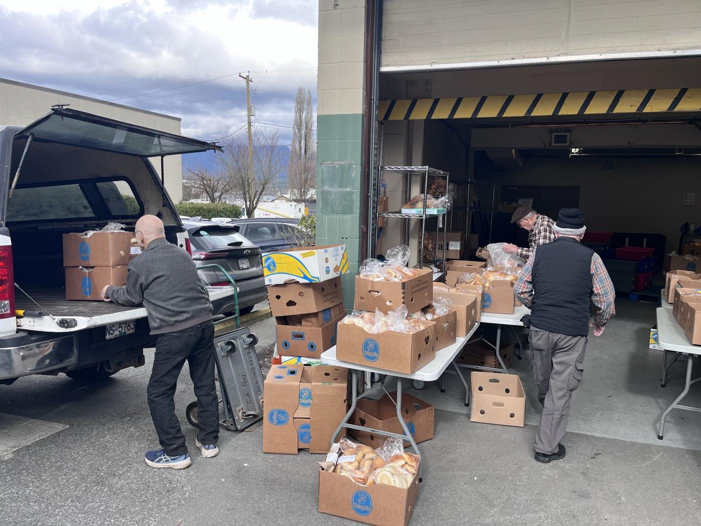 Volunteers unloading bread and boxes of donations from a truck